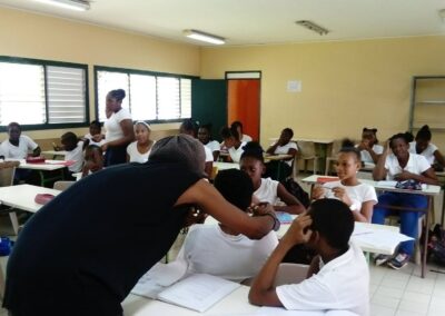 Une animatrice engage activement une classe d'élèves attentifs dans une activité pédagogique en Guadeloupe, soulignant l'importance des actions culturelles dans l'éducation.
